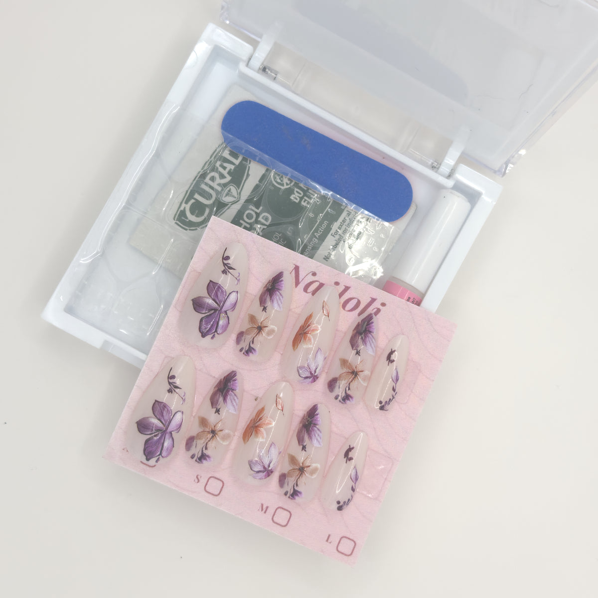 Stiletto floral set on its card beside the open kit with nail file, prep pad, and nail glue