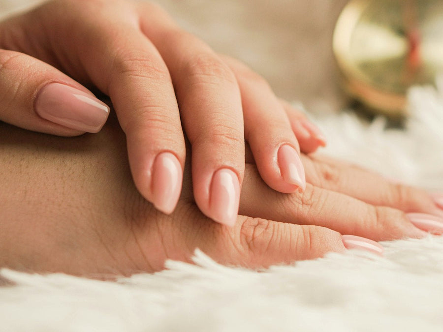 Hands with short, healthy natural nails resting on a soft cream background