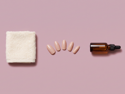 Flat lay of a towel, removed press-on nails, and cuticle oil