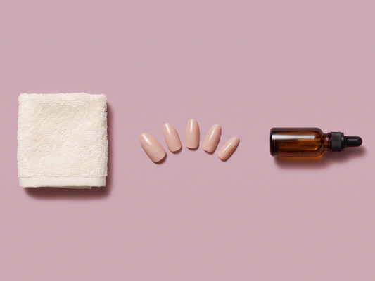 Flat lay of a towel, removed press-on nails, and cuticle oil