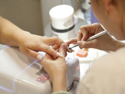 Nail technician doing a gel manicure at a salon with a UV lamp