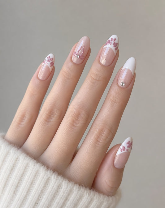 Hand wearing sheer blush almond press-ons with white French tips, pink bows, and gemstones