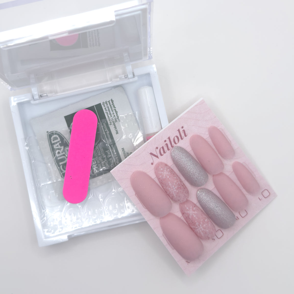 Set of false nails with a pink applicator and clear case on a white background