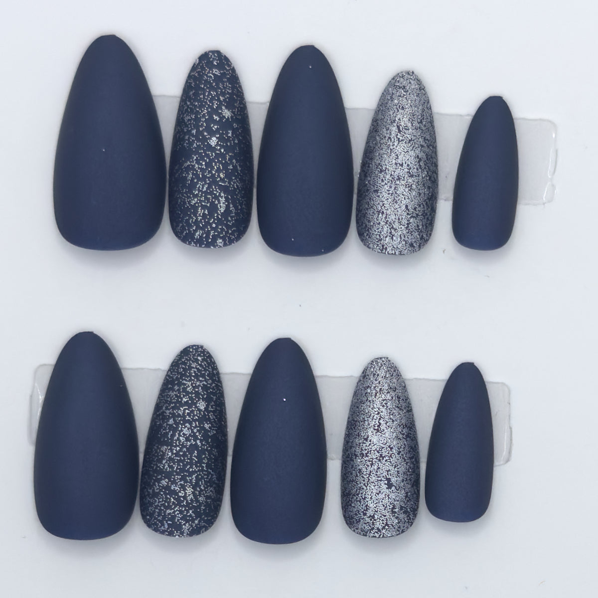 Close-up of matte navy almond press-ons with navy and silver glitter nails
