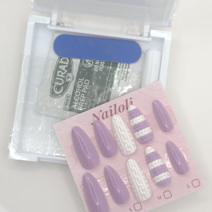 Set of purple and white striped false nails with a Curad alcohol prep pad in the background.