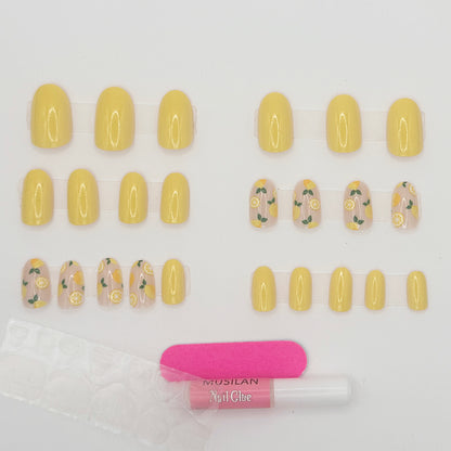 Set of yellow nail extensions with floral designs and a bottle of nail glue on a white background