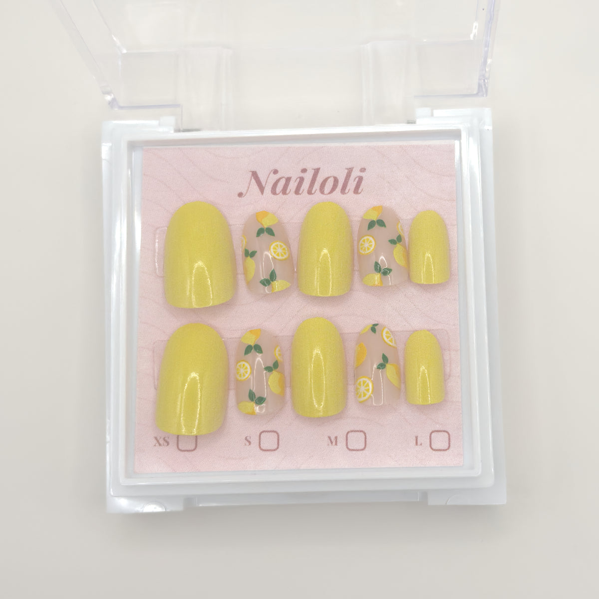 Set of yellow nail polish with floral designs in a clear packaging on a light pink background.
