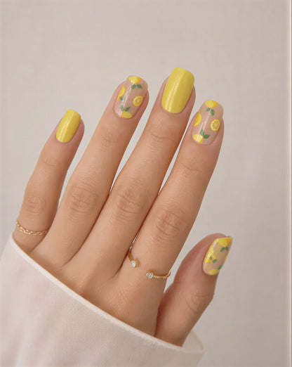 Hand with yellow nail polish featuring floral designs on a neutral background
