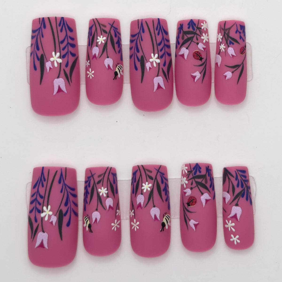 10 magenta press-ons in two rows with purple wisteria, white flowers, and small bee details