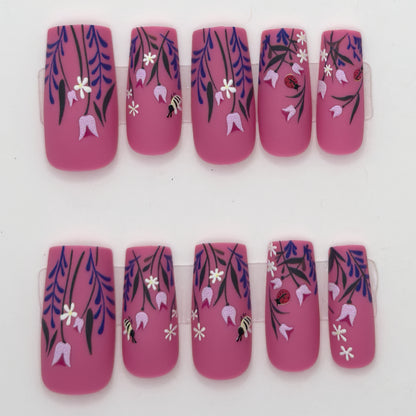 10 magenta press-ons in two rows with purple wisteria, white flowers, and small bee details