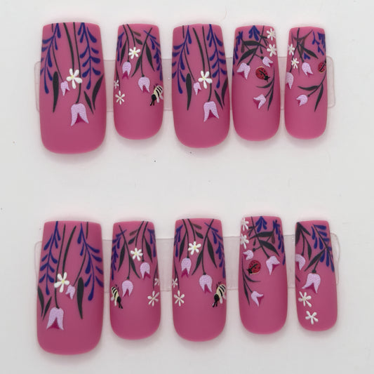 10 magenta press-ons in two rows with purple wisteria, white flowers, and small bee details