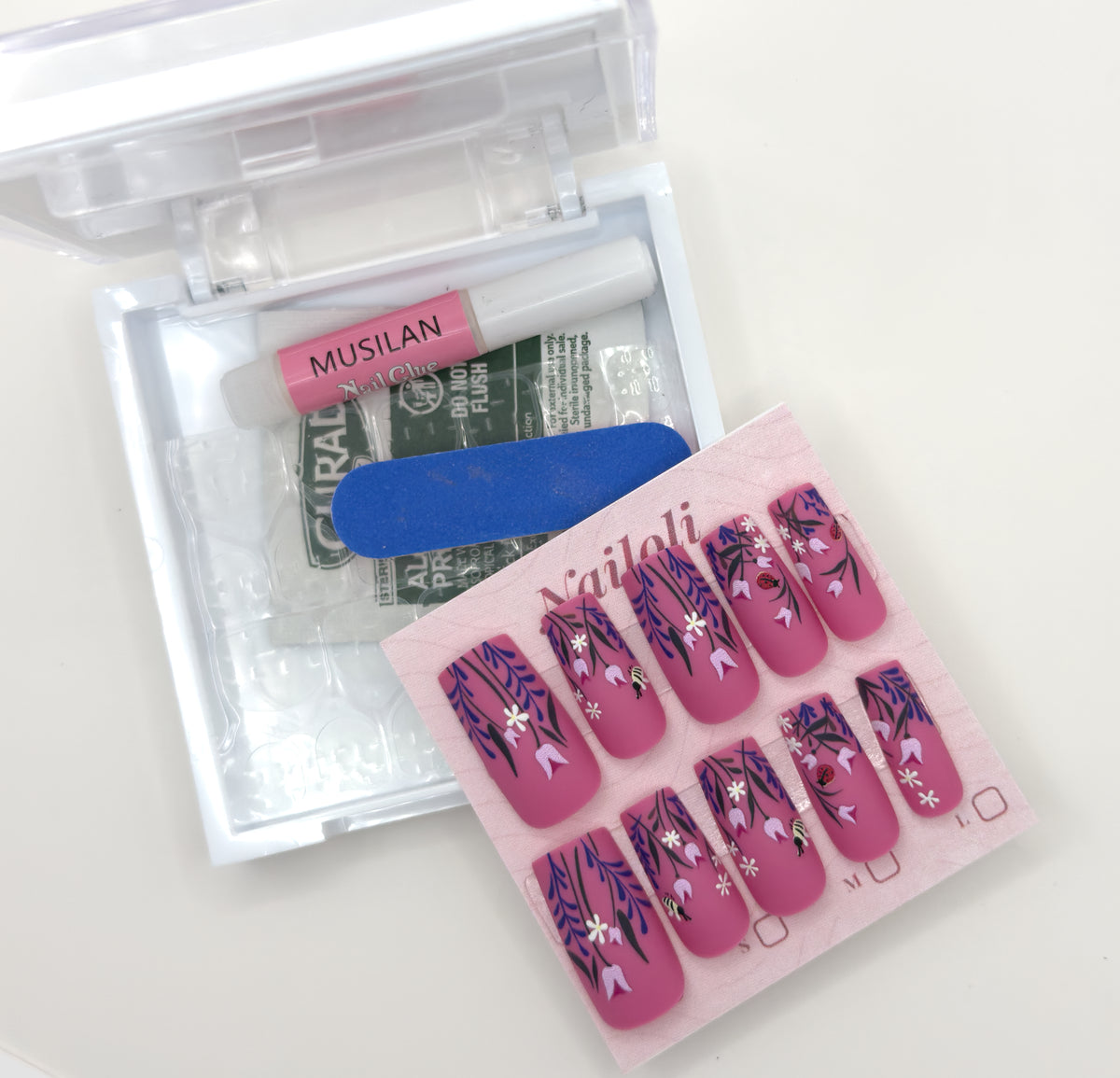 Magenta botanical set on its card beside the open kit with nail glue, prep pad, and nail file