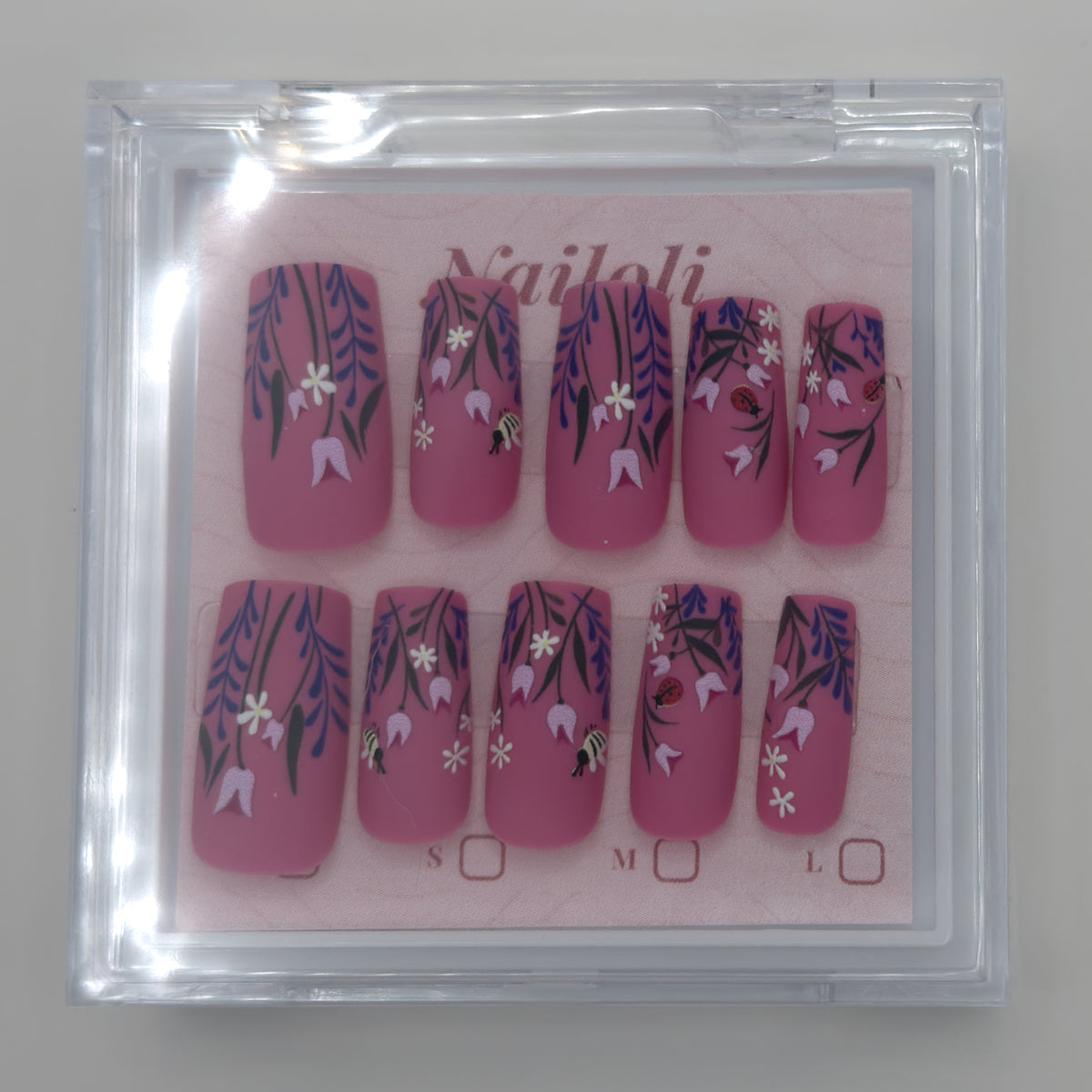 Magenta botanical set on its backing card inside the closed clear Nailoli case