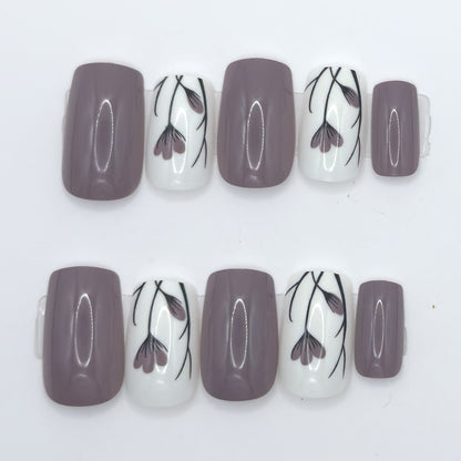 10 press-ons in two rows: glossy taupe nails and white nails with black and mauve tulip line art