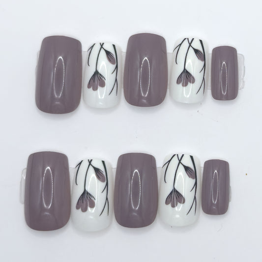 10 press-ons in two rows: glossy taupe nails and white nails with black and mauve tulip line art