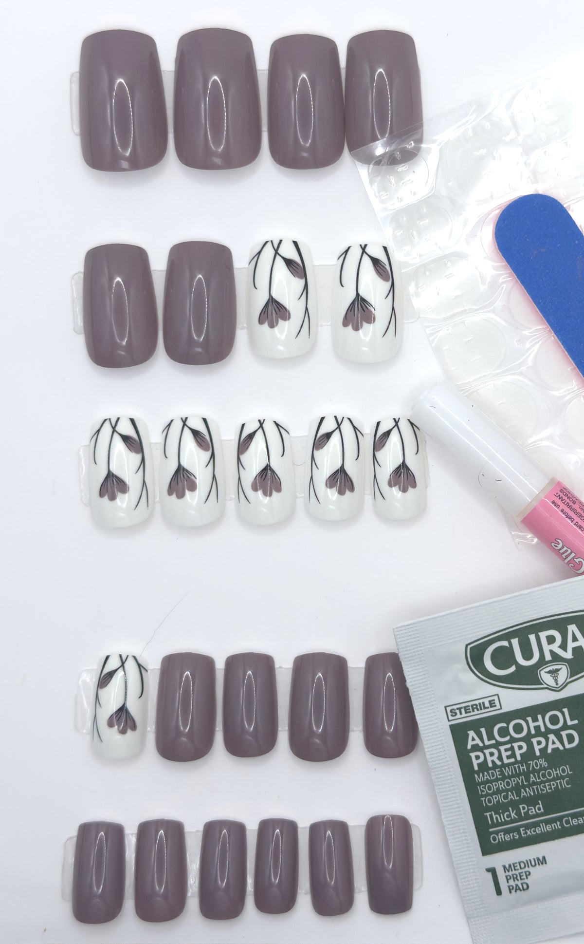 Full taupe floral set beside adhesive tabs, a nail file, and nail glue