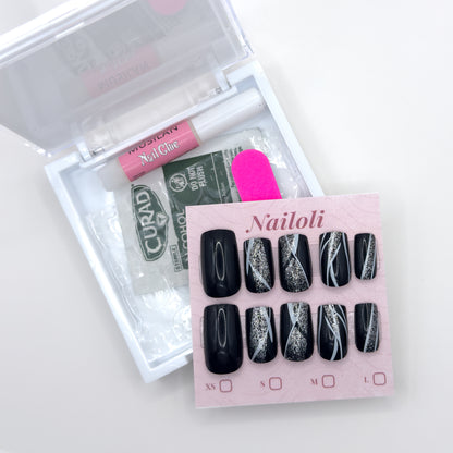 Glossy black set on its card beside the open kit with glue, prep pad, adhesive tabs, and nail file