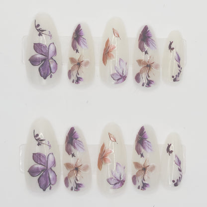 Close-up of milky stiletto press-ons with purple and peach watercolor flowers