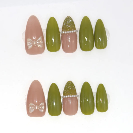 Ten long almond press-ons in olive green and rosy nude, with a clear bow on each thumb and a pearl line on each middle nail