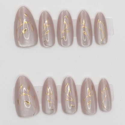 Set of false nails with gold leaf design on a white background