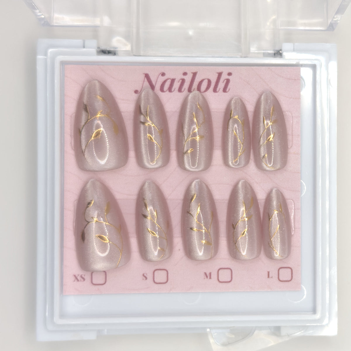 Set of nail extensions with gold leaf design in a 'Nailoli' branded box.
