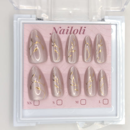Set of nail extensions with gold leaf design in a 'Nailoli' branded box.