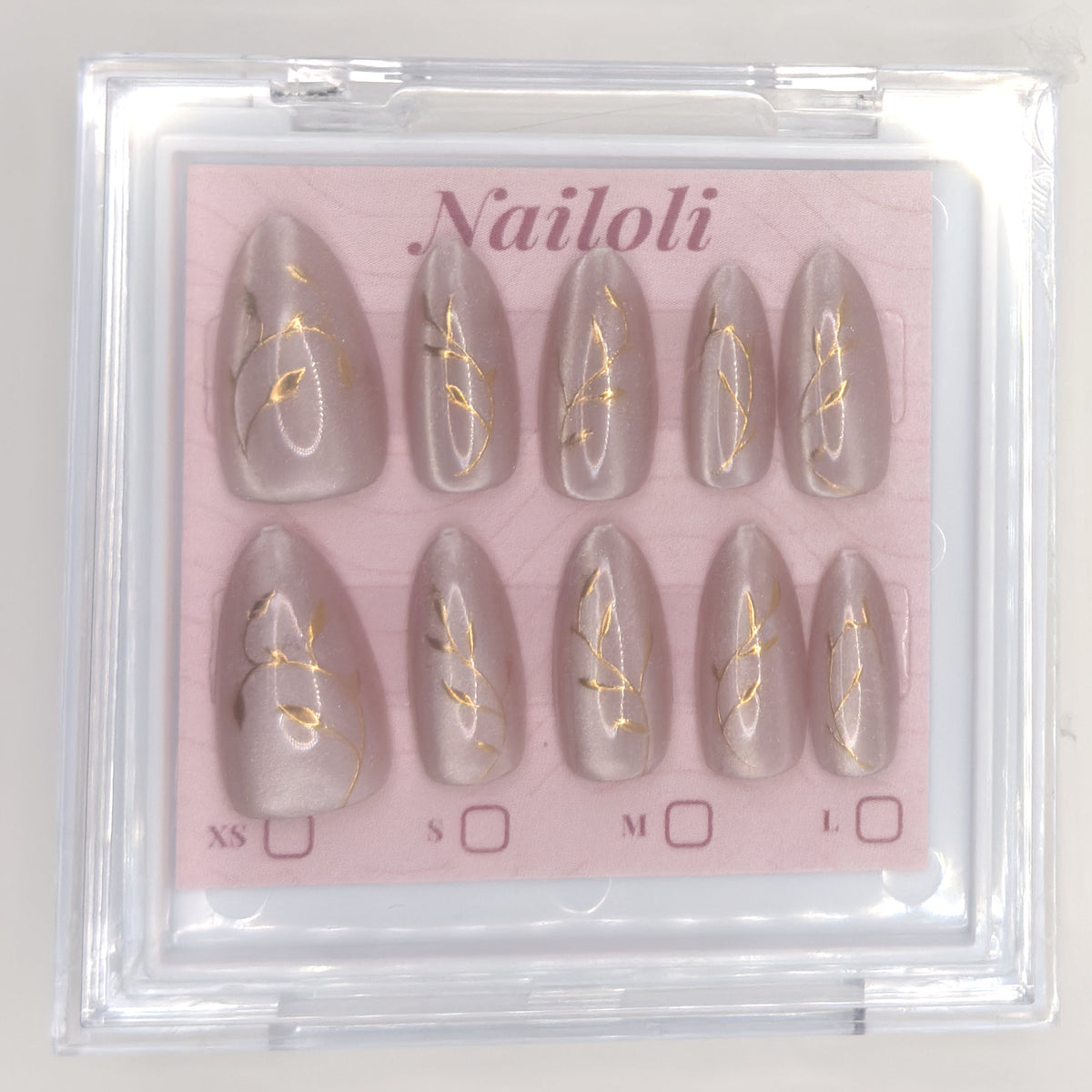 Set of nail extensions with gold leaf design in a 'Nailoli' branded box.