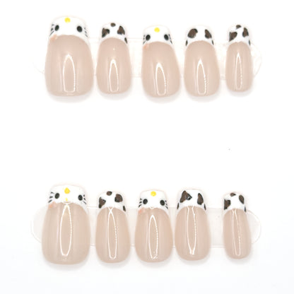 10 sheer blush coffin press-ons in two rows with cat face tips and black and white cowprint tips