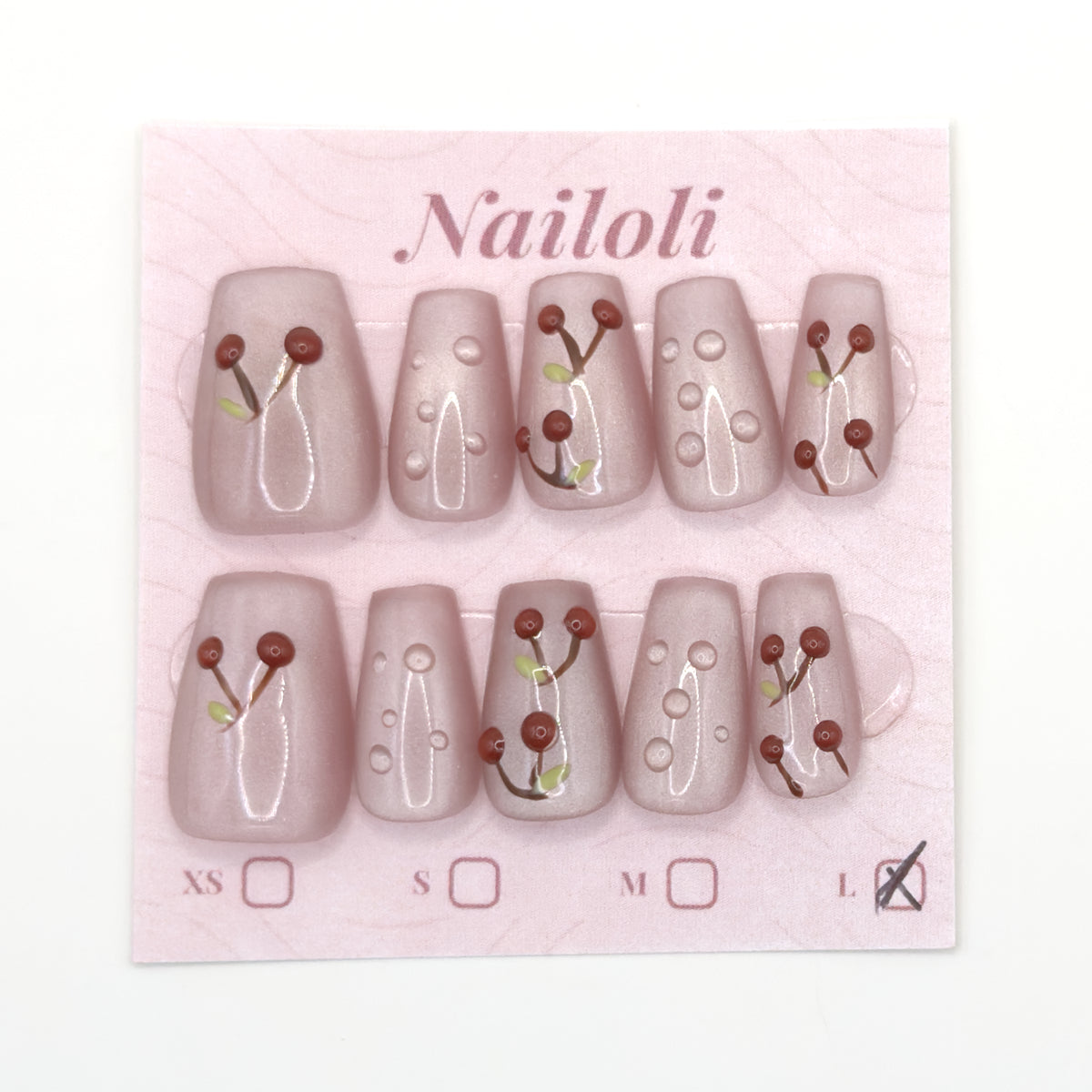 Blush nails with painted cherries and dewdrop accents on the Nailoli backing card, size L marked