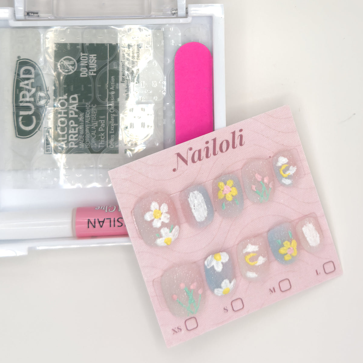 Daisy and tulip set on its card beside the open kit with nail glue, prep pad, and nail file