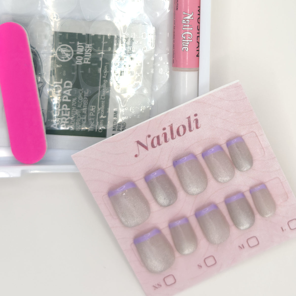 Silver holographic set on its card beside the open kit with nail file, prep pad, and nail glue