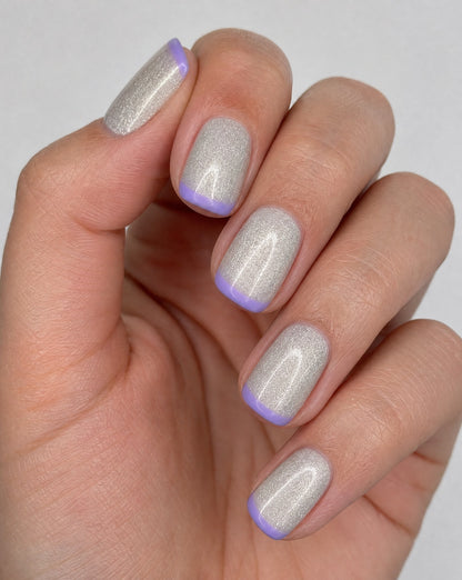Hand wearing silver holographic square press-ons with lavender French tips