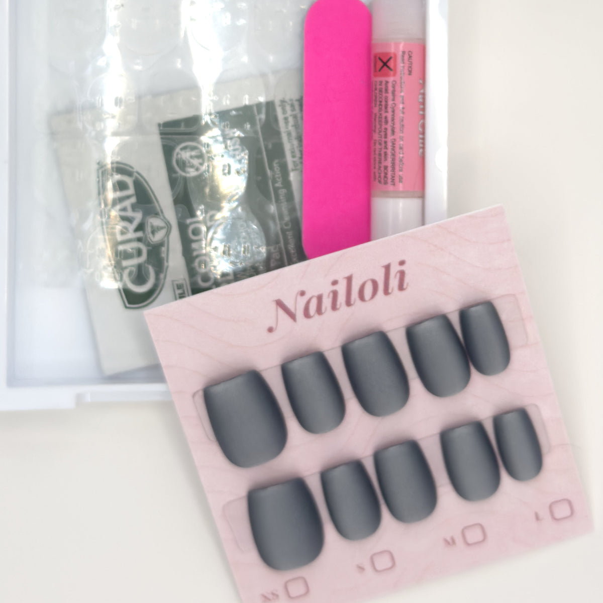 Matte charcoal set on its card beside the open kit with nail glue, prep pad, and nail file