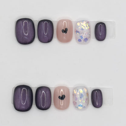 10 press-ons in two rows: velvet plum nails, a nude nail with a black heart, and a glitter nail