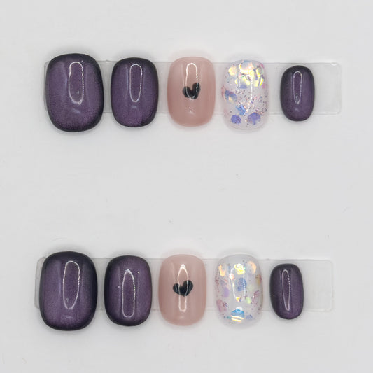 10 press-ons in two rows: velvet plum nails, a nude nail with a black heart, and a glitter nail