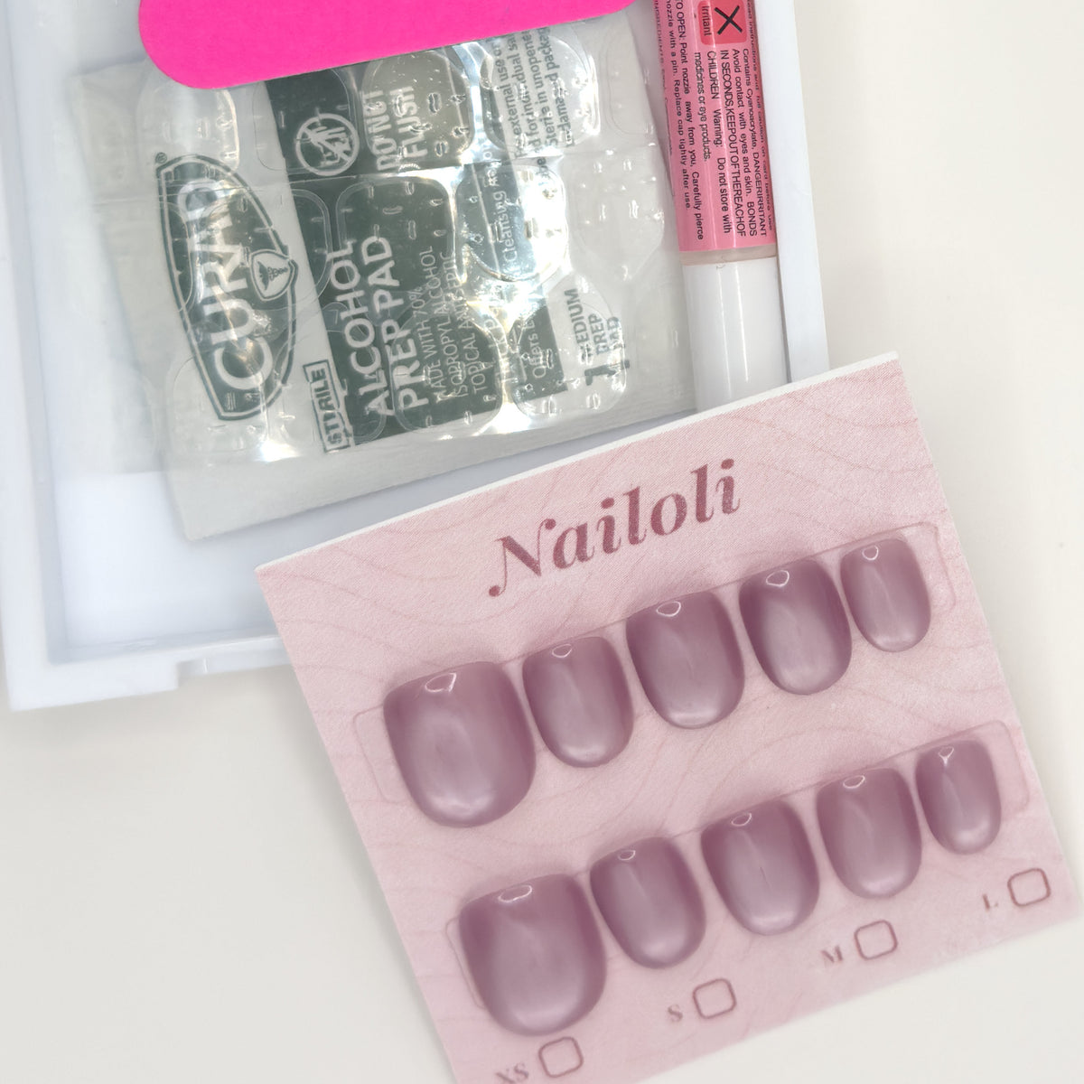 Dusty mauve set on its backing card beside the open kit with alcohol prep pad and nail glue