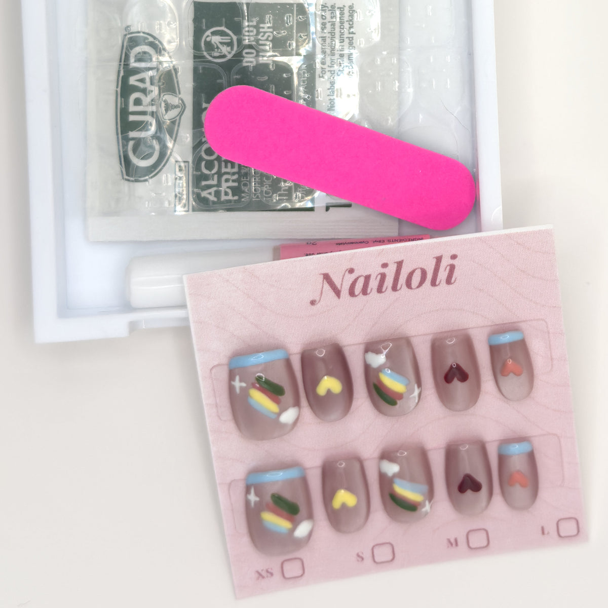 Taupe heart set on its backing card beside the open kit with alcohol prep pad and nail file