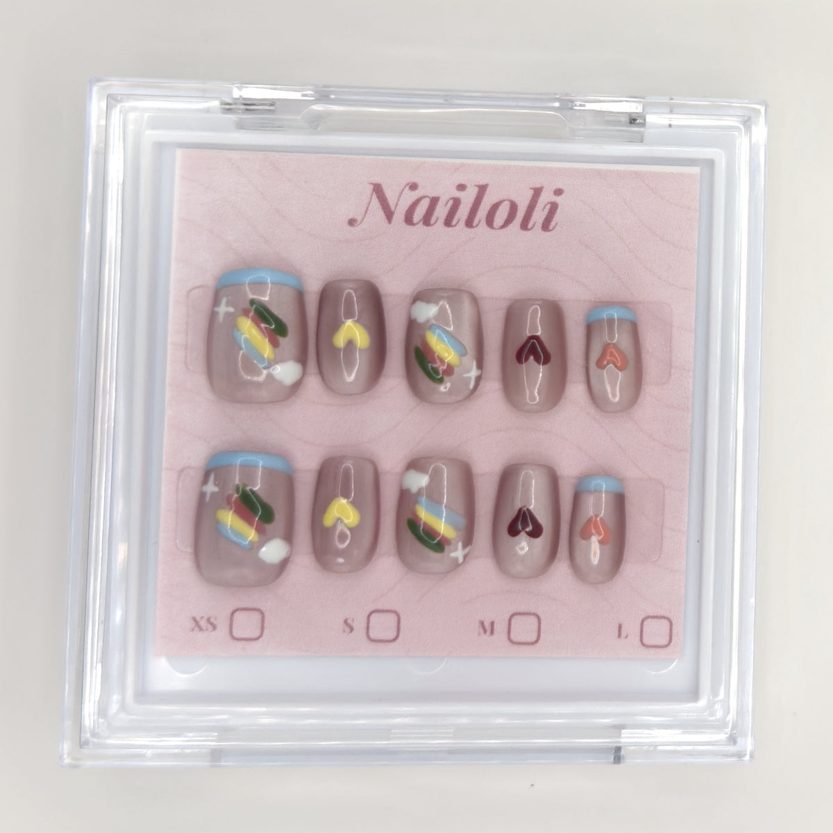 Taupe heart set on its backing card inside the open clear Nailoli case