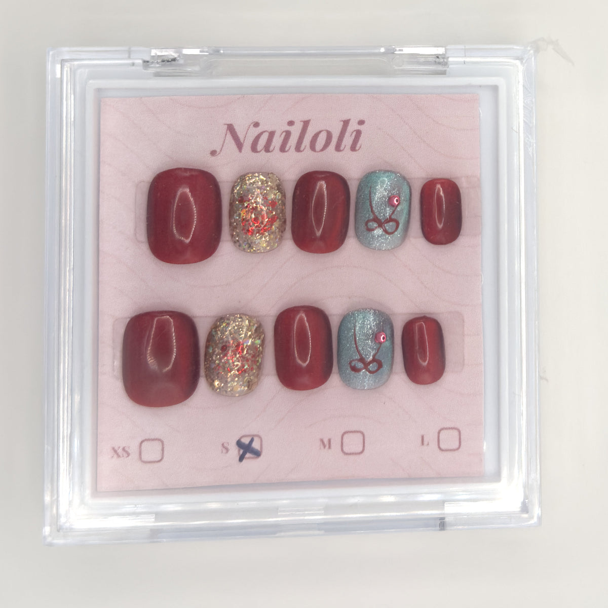 Burgundy glitter set on its backing card inside the closed clear Nailoli case
