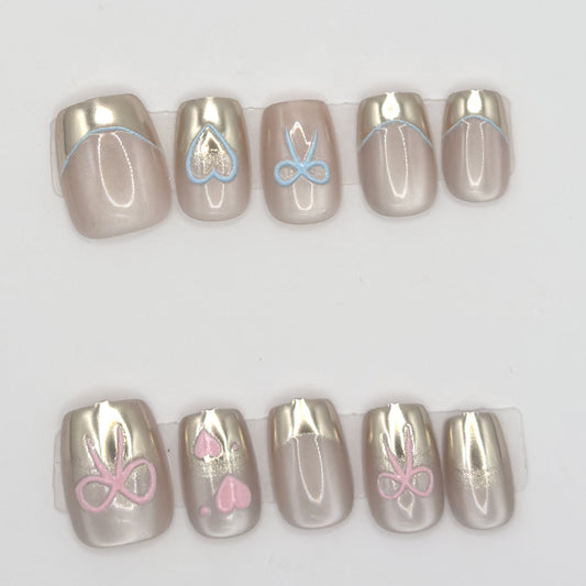 Close-up of 10 champagne chrome press-ons in two rows with blue and pink heart and bow line art