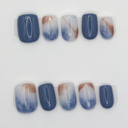 10 press-ons in two rows: solid slate blue nails and milky white nails marbled with blue and copper