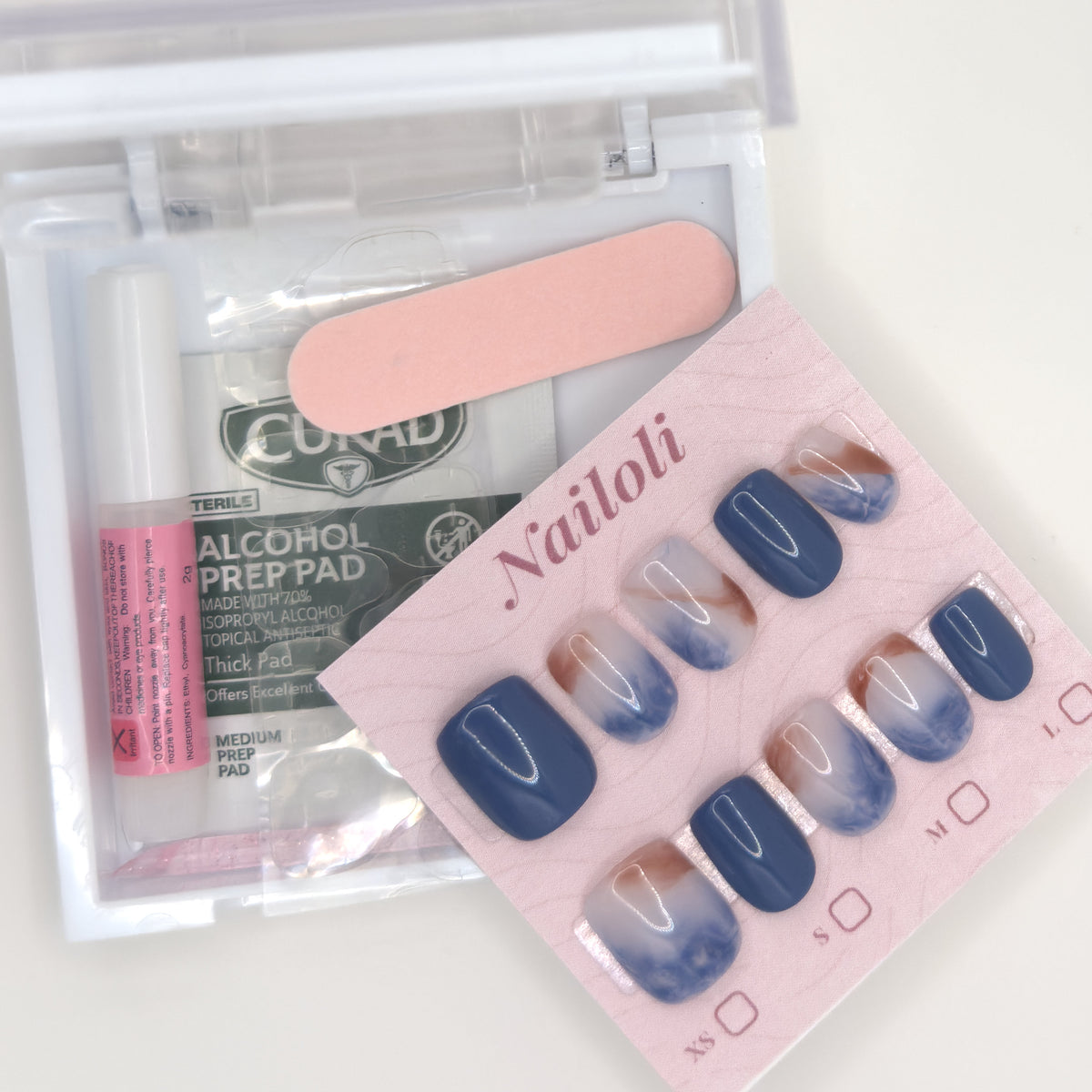 Ocean marble set on its card beside the open kit with nail glue, prep pad, and nail file