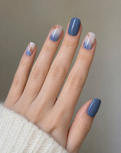 Hand wearing ocean marble square press-ons, slate blue and white nails marbled in blue and copper