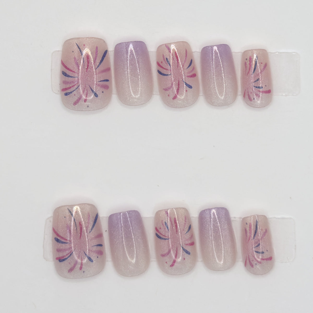 10 press-ons in two rows, alternating pink starburst line art and solid lavender ombre nails
