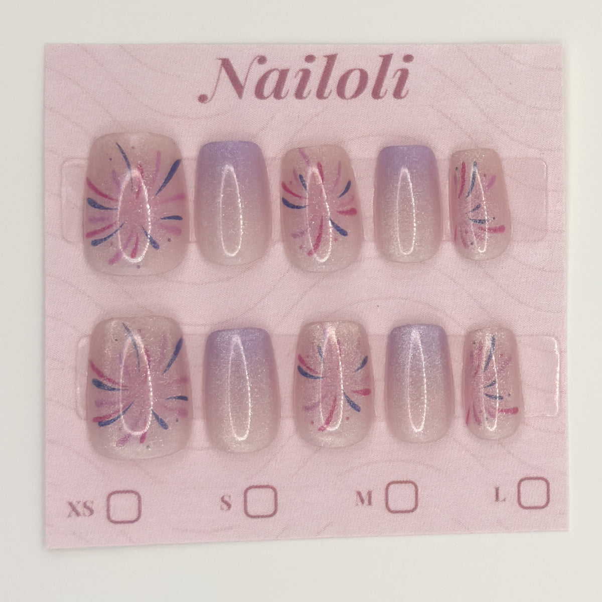 Lavender starburst nails on the pink Nailoli backing card with XS, S, M, and L size boxes