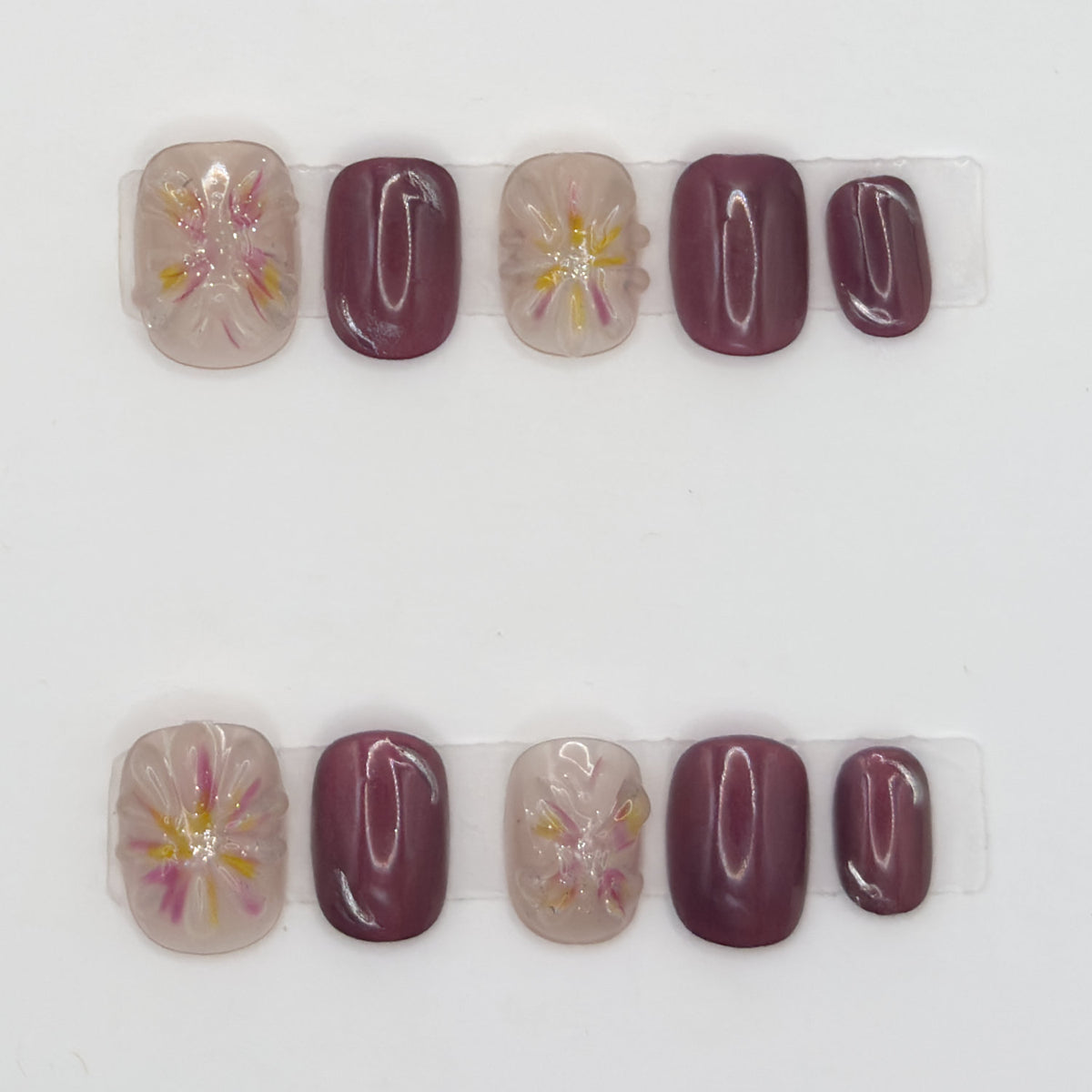 10 press-ons in two rows: glossy mauve nails and sheer nails with pink and yellow watercolor florals