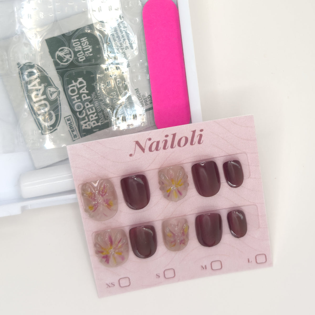 Mauve blossom set on its card beside the open kit with alcohol prep pad and nail file