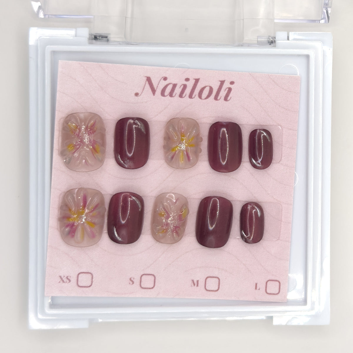 Mauve blossom set on its backing card inside the open clear Nailoli case