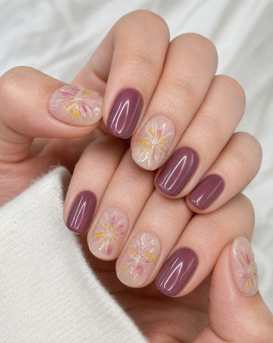 Hand wearing glossy mauve square press-ons with sheer accent nails of pink and yellow florals