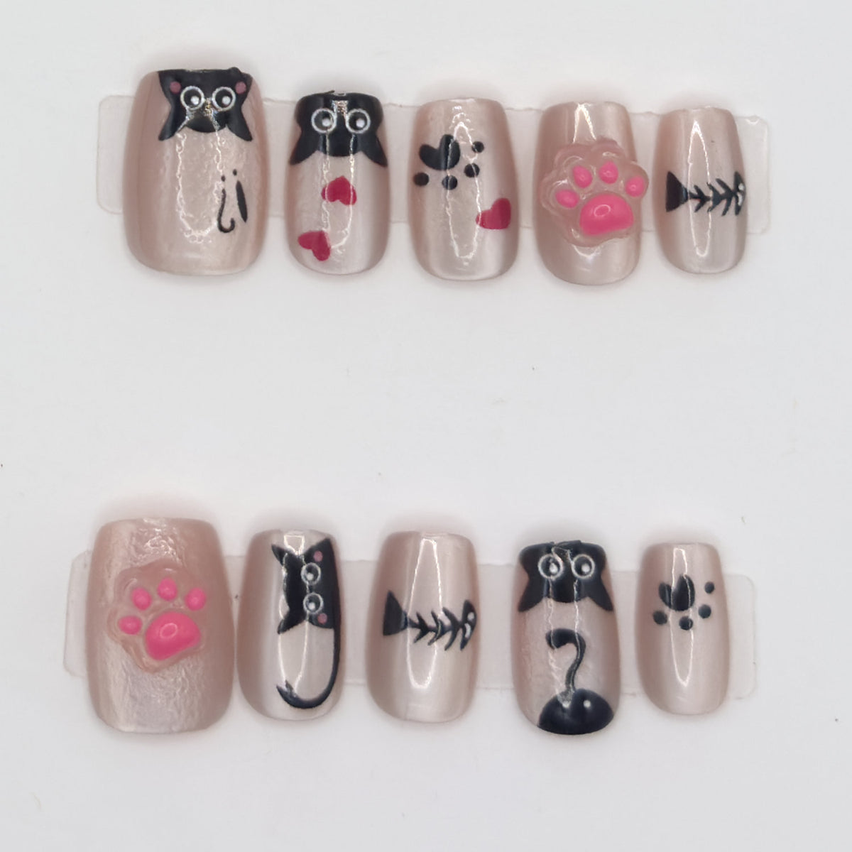 10 champagne press-ons in two rows with peeking black cats, pink 3D paws, fish bones, and paw prints